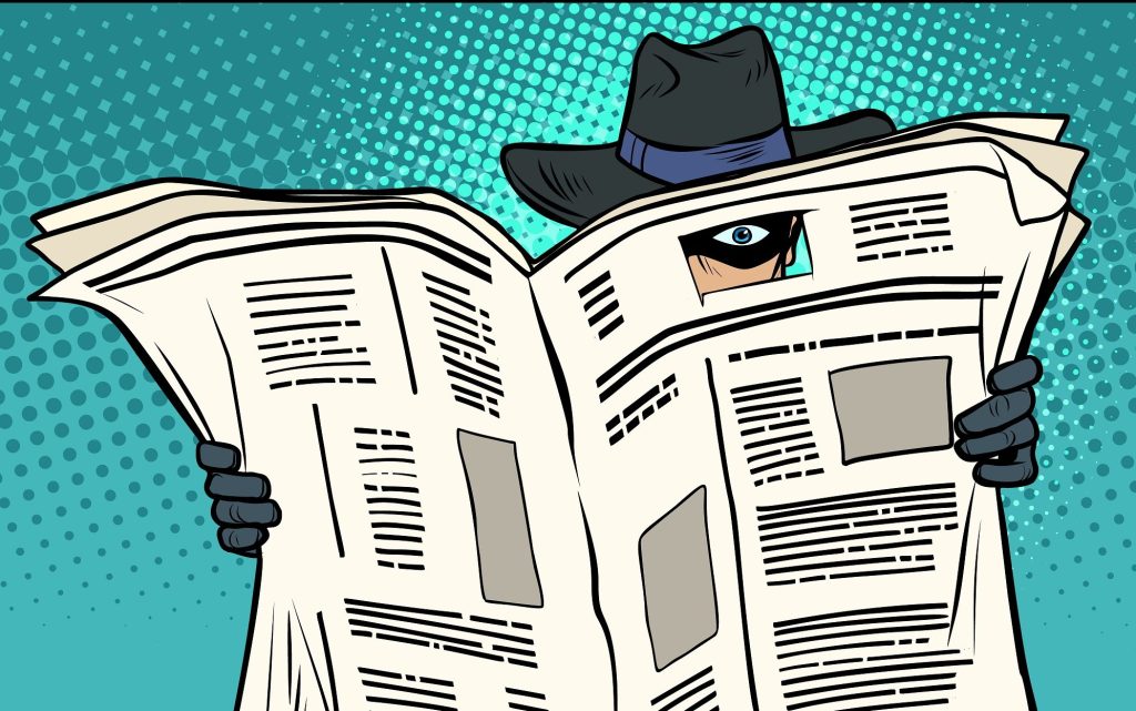 A cartoon of a spy hidden by a newspaper. All we see of him is his hat and gloved hands, and one eye: he has cut out a photo in the newspaper's front page and is staring through it to avoid being spotted.