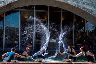 Dancers splashing water in outdoor performance 'Water Tight'.