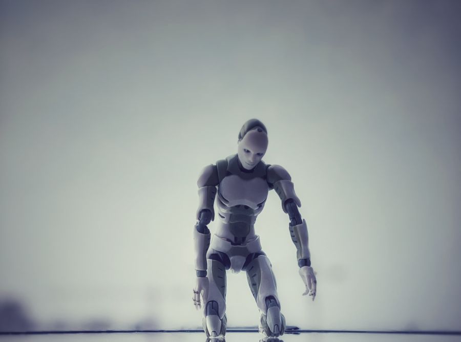 A white and grey human sized robot looking down against a grey sky.
