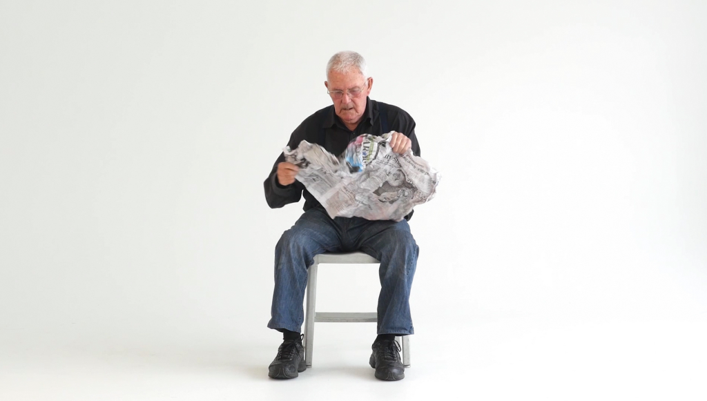 Picture of artist Jim Allen reading the newspaper