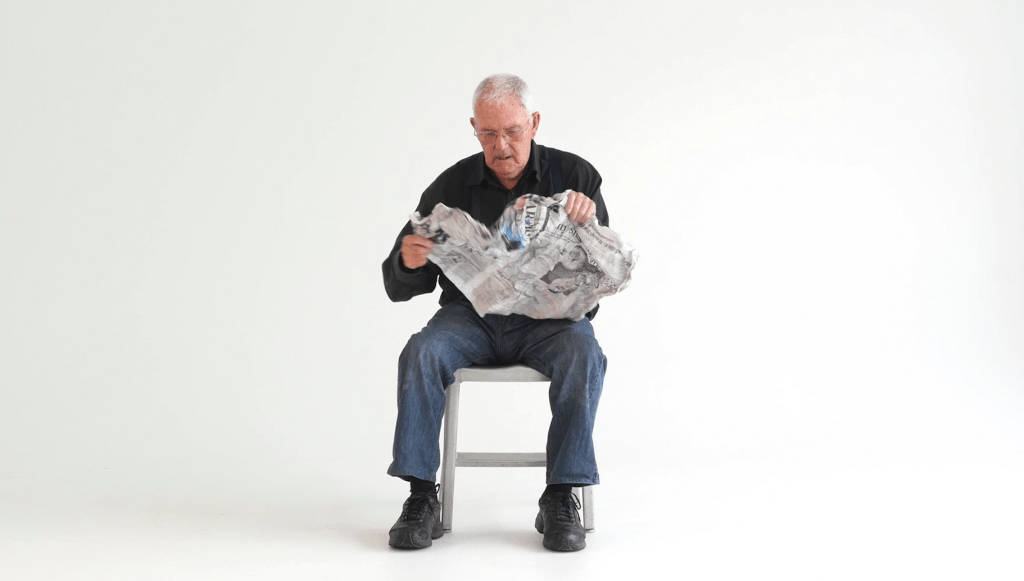 Picture of artist Jim Allen reading the newspaper