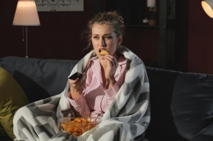 girl on couch eating chips watching television