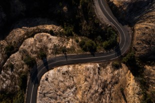 An aerial view of the winding road into Queenstown TAS highlighting the moonscape-like hills around the town.