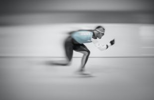 A dynamic photo of ice-skater who is moving so fast that he's almost a blur.
