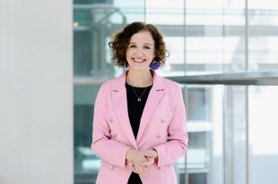 Woman (Kirsten Lacy) in a pink jacket smiling