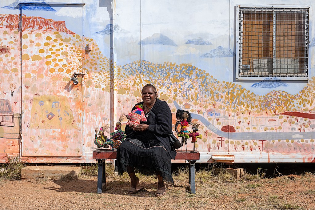 Aboriginal woman sitting in front of a mural