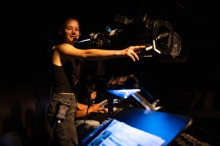 A WAAPA student smiles as she prepares to shine the spotlight she is working onto a performer.
