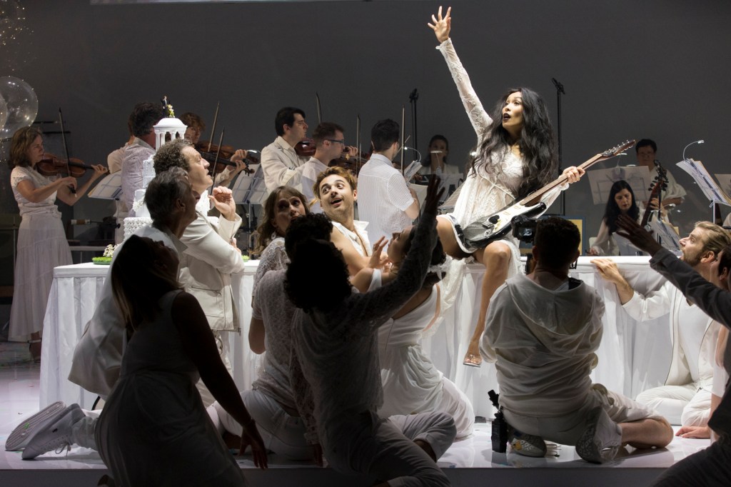 Australian Theatre Live launches accessible theatre online for students and educators, including Platee by Pinchgut Opera. Image shows performers on stage surrounding a young woman dressed in white with upthrust arm.