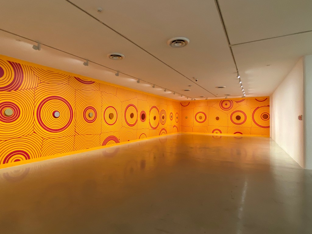 Savanhdary Vongpoothorn. Large orange and red wall-based artwork that wraps around a gallery.