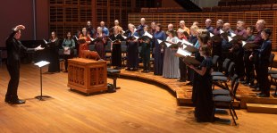 A conductor on the left conducting the Sydney Chamber Choir on the right.