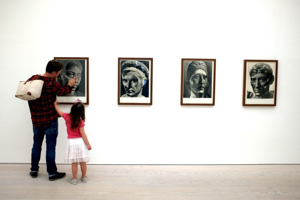 Man and small girl looking at art in a gallery