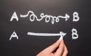 White chalk on a black board. The top line is the letter A connected in squiggly line to the letter B, the bottom line is the letter A with a straight line to letter B.