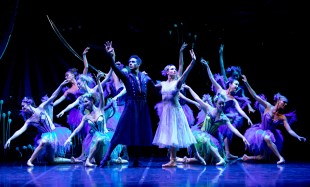 A Midsummer Night's Dream. Image is of ballet dancers against a black backdrop, fairies all reaching up with one arm and the other reaching down, behind two principals - a male in black and a female in traditional white tutu - in the same pose.