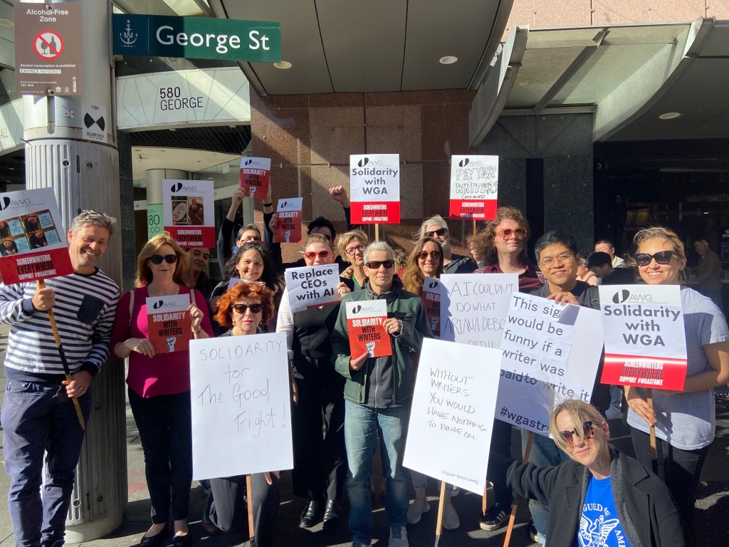 writers guild. Image shows group of people holding placards and facing camera.