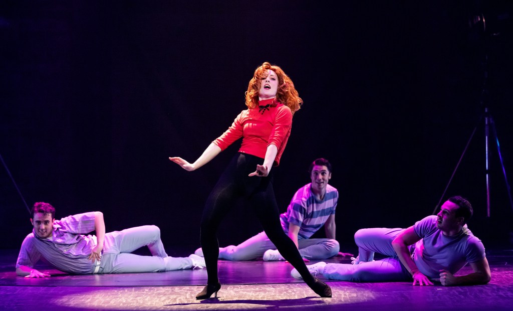 Elvis. Woman in black tights and red jumper dancing with red hair.