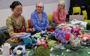 Hiromi Tango demonstrating the ritual wearing of all donated items prior to her incorporating parts of them into her installations during a workshop at Museum of Brisbane in October 2023. Photo: ArtsHub.