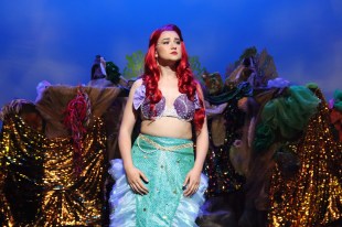 the little mermaid. Woman with long red hair and mermaid costume stands on stage.