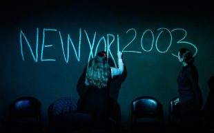 Myth, Propaganda and Disaster and the Heirs of America. Image is a woman standing in front of a blackboard writing, the blackboard has NEW YORK 2003 in large letters.