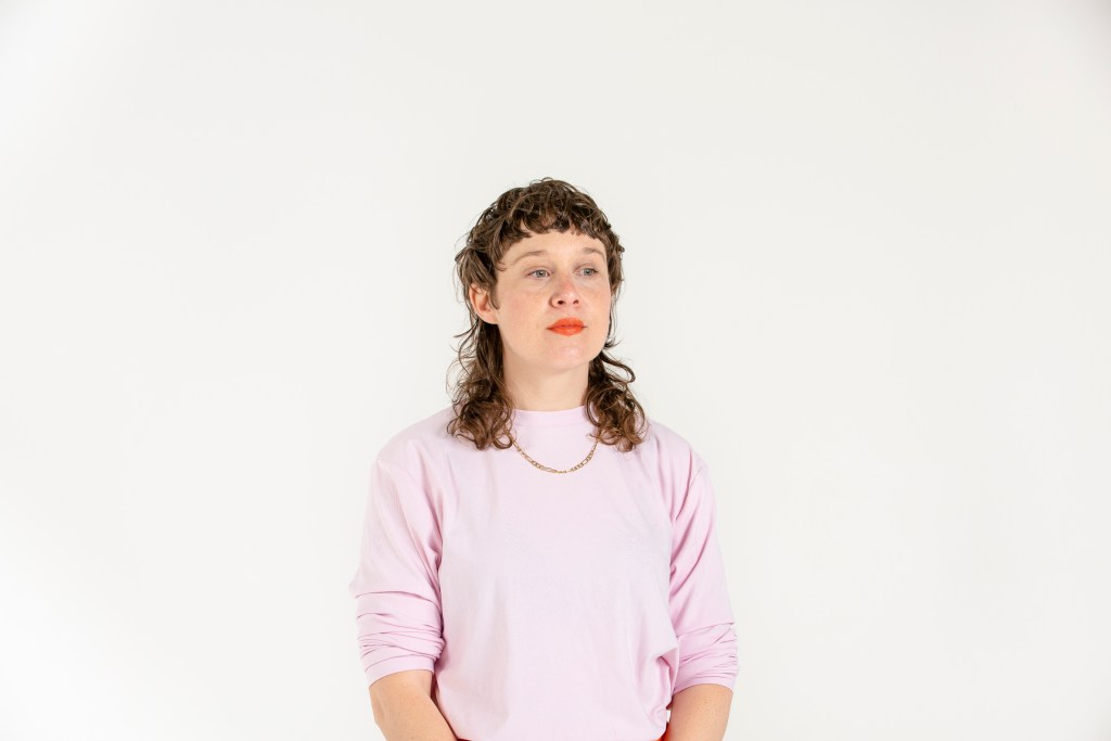 other work. Woman in pink jumper with shoulder length mullet.