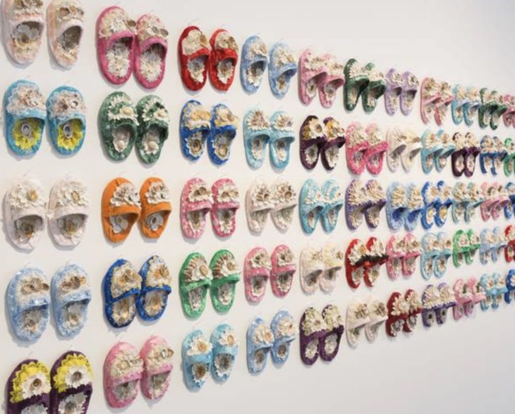 Aboriginal art. view of shoes covered in shells hanging on gallery wall