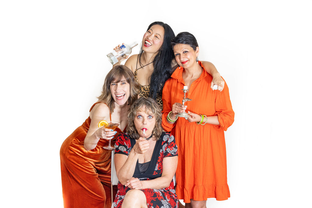 Tight Mums. Four women dressed in orange or black and red. One is seated, another is crouching over and the other two standing.