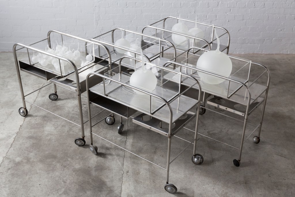 metal trolleys with white handblown glass elements on top as part of art installation