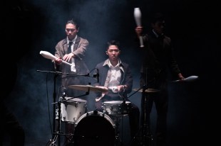 Mr. III三III. Image is three men with juggling pins. One is seated in front of a drum kit.