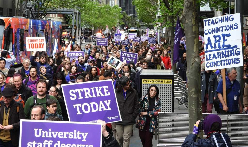 Strikes. University of Melbourne protesters march in solidarity with striking staff of RMIT University in CBD of Melbourne, October 2023. They are wearing purple and carrying placards. Photo: Darren Hocking.