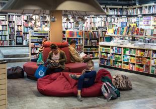 Read. Image shows people sitting in a library on beanbags readying.
