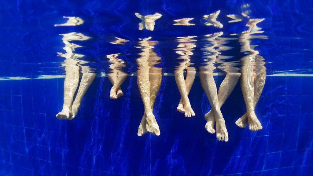 Arts news. Underwater photo of bare feet in swimming pool
