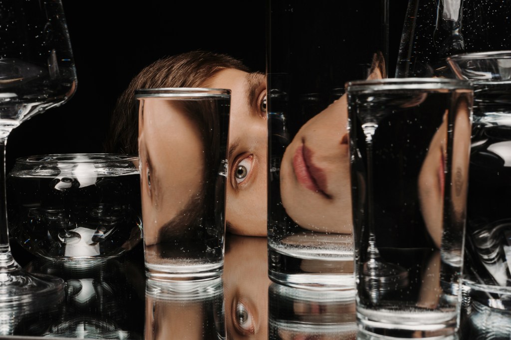 posthuman theatre. A photograph of a woman's face as reflected in numerous glasses of water.