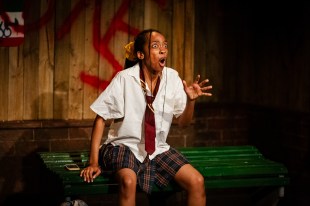 Chewing Gum Dreams. Image is of a black teenage girl sitting on a block, wearing school uniform and looking shocked.