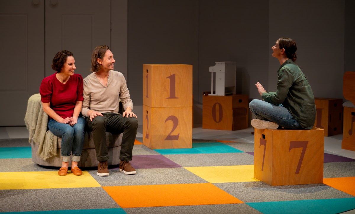 Welcome to Your New Life. Image is of three people sitting in a Play School like set, a man and a woman on a couch, looking expectant and listening intently, and a third person on a cube with the number 7 on the side talking to them.