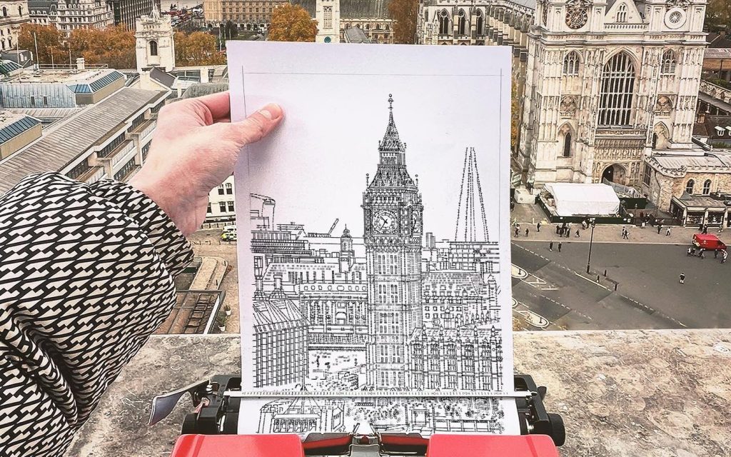 Typewriter artist James Cook recreates view of Big Ben on site. Image is a hand holding up an image of Big Ben while looking down from a rooftop opposite the Palace of Westminster in London.