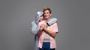 IRL. Image is a boy in a pink shirt with a boy in a koala onesie wrapping his arms around him.