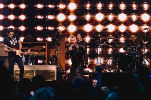 Mushroom 50. Image is of a rocker belting out a song with a band behind him.