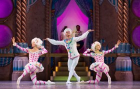 Nutcracker. Image is three dancers, two in pink with puffy pantaloons on bended knees and the third in the middle in light blue in a dancing pose with both arms raised to the sides.