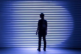 Fremantle Biennale. image is a stripey spotlight backdrop with the silhouette of a single figure standing in front of it.