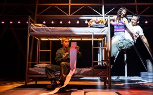 Vietgone. Image is of a stage with a man in army fatigues sitting on a bottom bunk and reading a very very long letter, while a grinning man and woman hang off the top bunk.