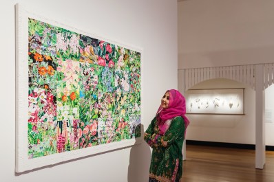 Rearranged: Art of the Flower. Image is a woman in a red headscarf looking at a large colourful painting of flowers on a gallery wall.