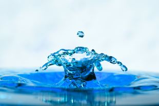 arts appointments. A close-up photo of a droplet of water creating a splash pattern in miniature.