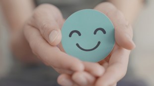 Culture. Wellbeing. Hands holding a blue drawing of a smiling face