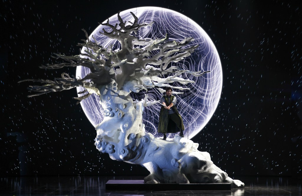 Die Walküre. A Wagnerian opera singer on a gnarled and bent white tree with a huge white moon projection behind them.