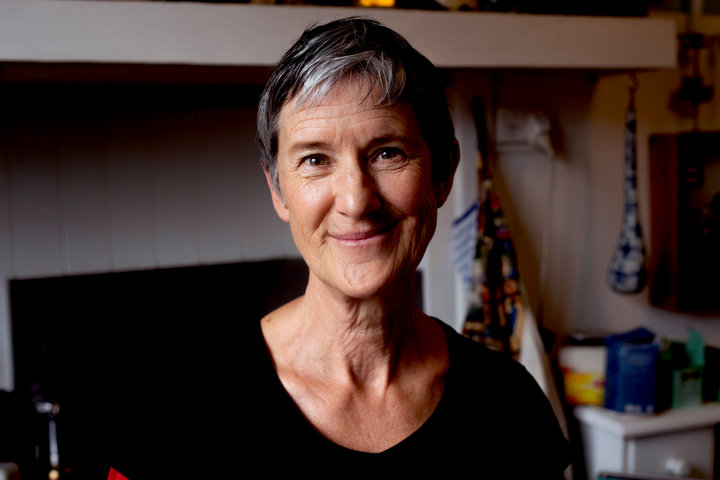 Sue Giles. Headshot of woman with short grey hair and black scoop neck top, she is smiling at the camera.