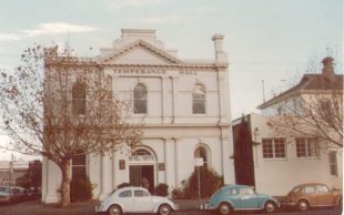 Exterior photo of Temperance Hall. Image: Supplied. Vintage photo showing a white brick two-storey building with the words 'TEMPERANCE HALL" on it and several Volkswagon Beetle cars parked in front on the street.