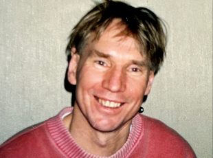 Ted Hopkins. Image is a smiling man in a red jumper.