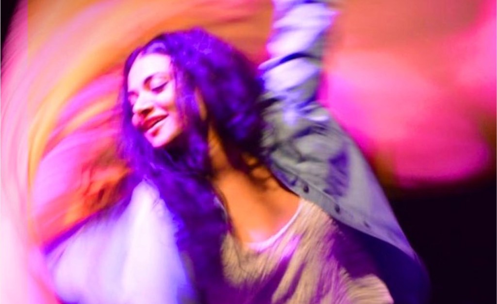 creative industries policy. Image is a young woman dancing in a swirl amid a blur of pink and orange.