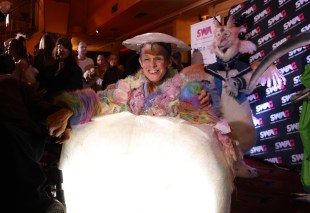 Wearable Art. Woman smiling and wearing colourful wearable art based on her wheelchair. Sitting in foyer of Enmore Theatre.