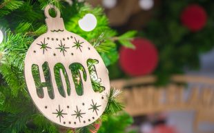 Photo: Arisa Chattasa via Unsplash. Photo of a bauble made out of wood with the word ‘HOPE’ engrained on it, hanging from a Christmas tree.