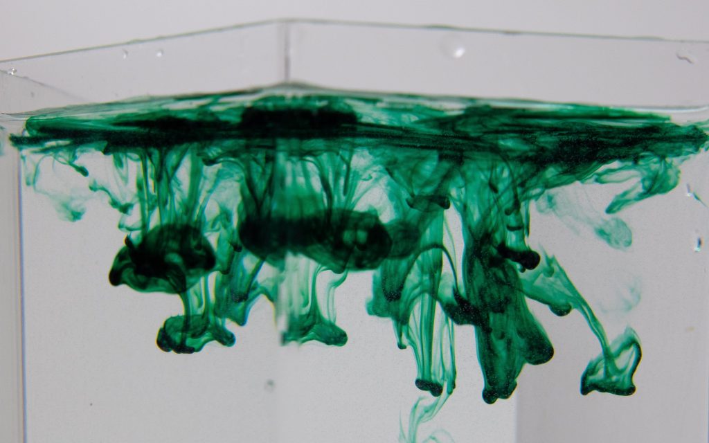 Colonial. Photo: Jill Burrow via Pexels. Green ink dropped into a clear glass of water.